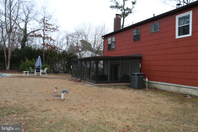 view of yard featuring central air condition unit and a sunroom