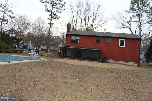 back of house featuring a patio, a covered pool, cooling unit, and a sunroom