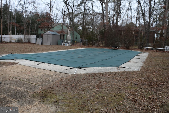 view of pool with a diving board, a patio area, and a storage shed