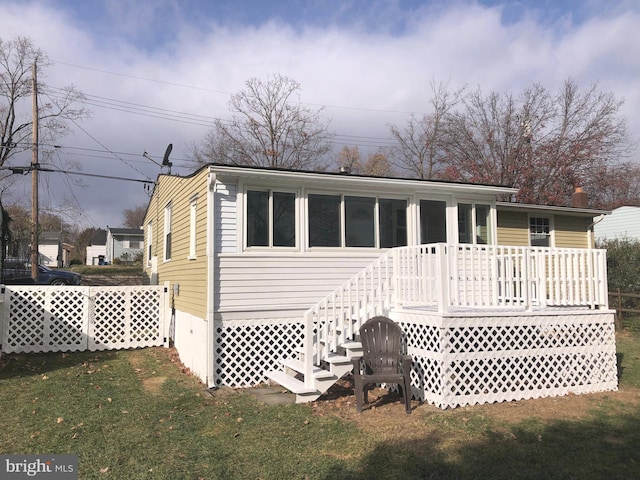 rear view of house with a wooden deck and a lawn