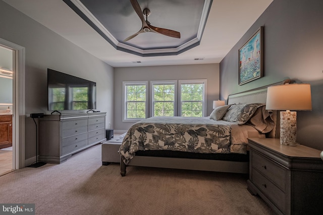 carpeted bedroom featuring a tray ceiling and ceiling fan