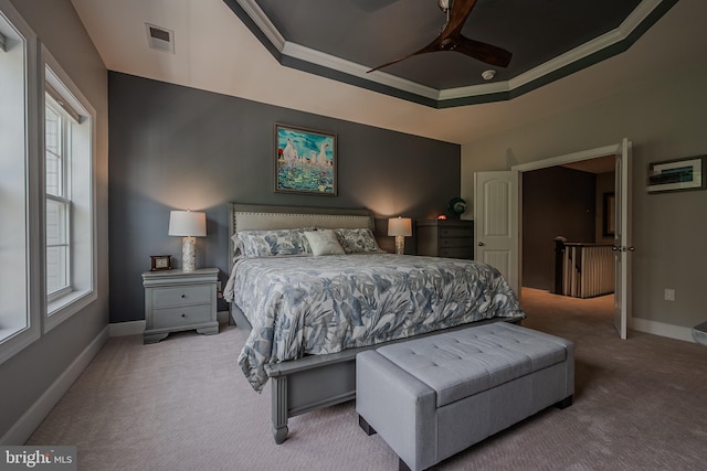 carpeted bedroom featuring a raised ceiling, ceiling fan, and ornamental molding