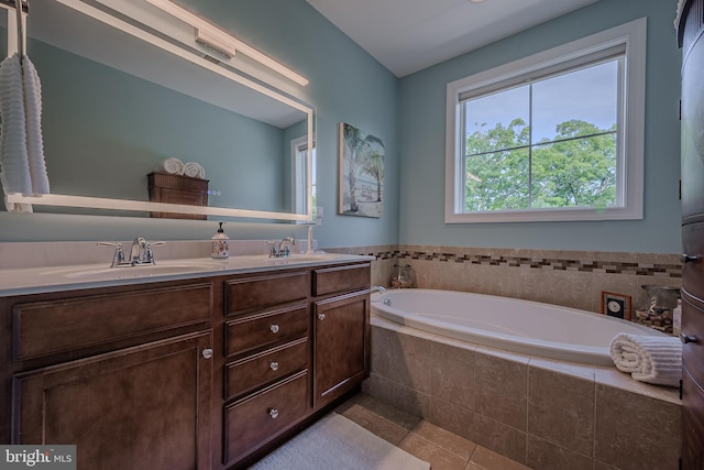 bathroom with tile patterned flooring, vanity, and a relaxing tiled tub