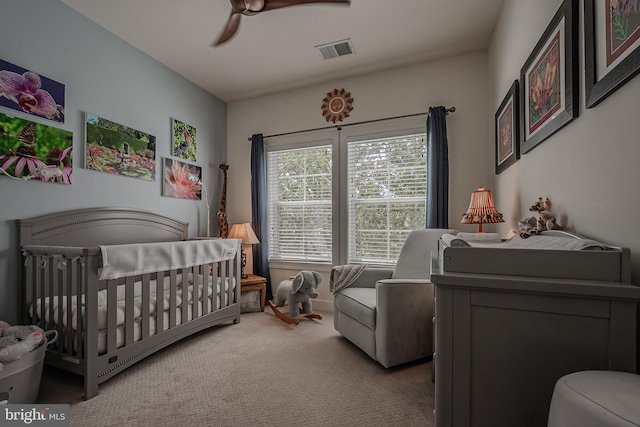 bedroom featuring carpet flooring, ceiling fan, and a crib