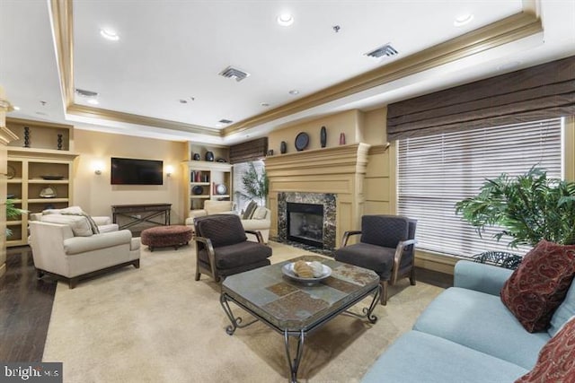 living room with a tray ceiling, a high end fireplace, and light wood-type flooring