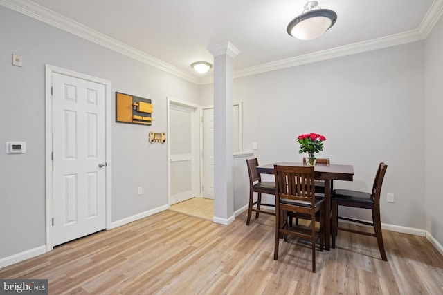 dining space with light hardwood / wood-style flooring, ornamental molding, and ornate columns