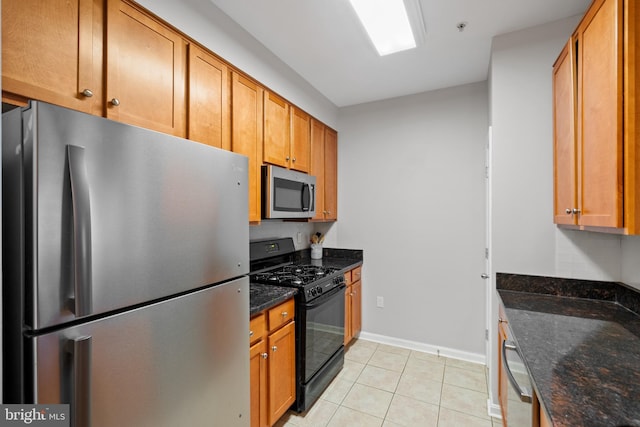 kitchen featuring light tile patterned flooring, dark stone countertops, and appliances with stainless steel finishes