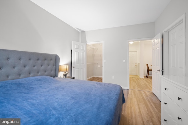 bedroom with a walk in closet and light hardwood / wood-style flooring