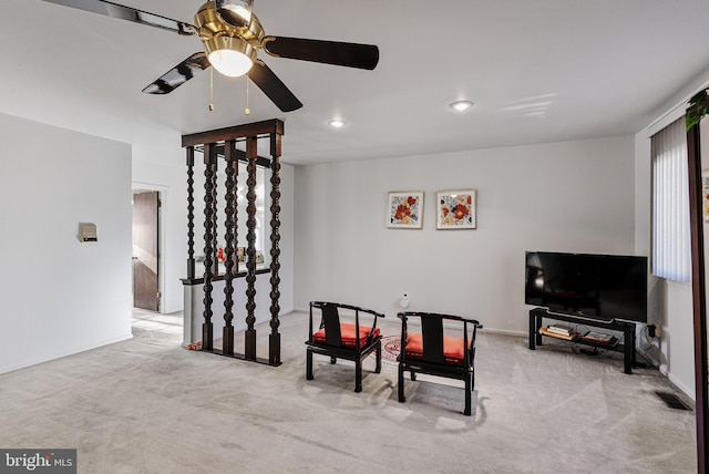 living area with light colored carpet and ceiling fan