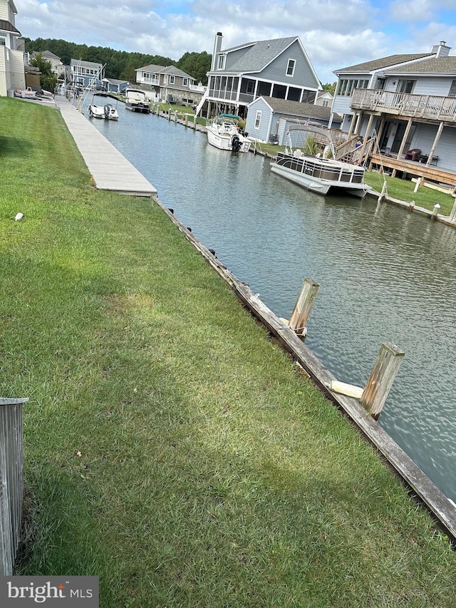 dock area with a water view and a yard