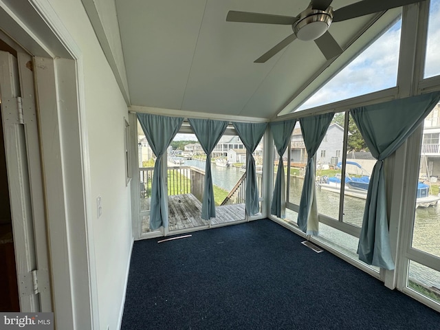 unfurnished sunroom featuring ceiling fan, a water view, and vaulted ceiling