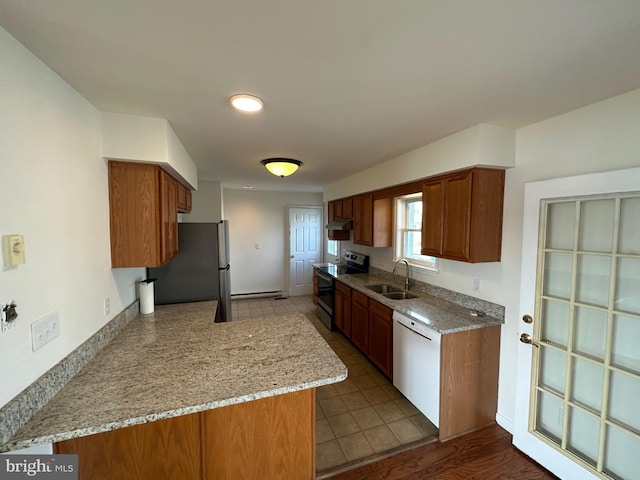 kitchen with light stone countertops, sink, kitchen peninsula, light hardwood / wood-style floors, and appliances with stainless steel finishes