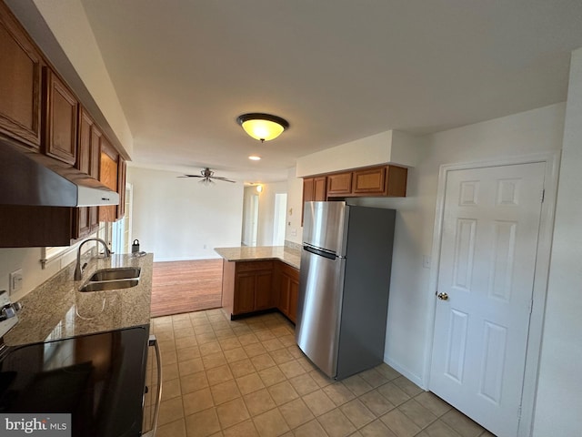 kitchen with kitchen peninsula, ceiling fan, sink, range, and stainless steel refrigerator