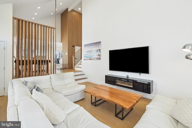 living area featuring stairway, recessed lighting, a towering ceiling, and wood finished floors