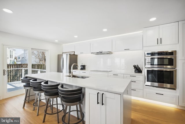 kitchen featuring a kitchen island with sink, appliances with stainless steel finishes, white cabinetry, and a sink