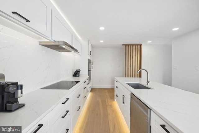 kitchen with light wood finished floors, recessed lighting, a sink, appliances with stainless steel finishes, and wall chimney exhaust hood