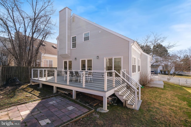 back of property featuring fence, a lawn, a chimney, a deck, and a patio area