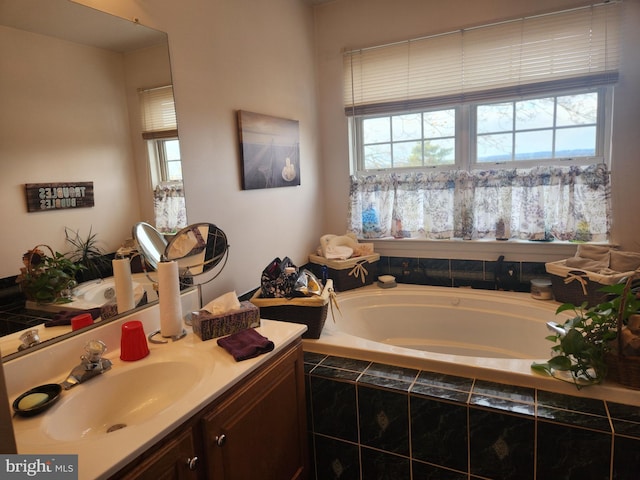 bathroom with vanity, tiled bath, and a healthy amount of sunlight