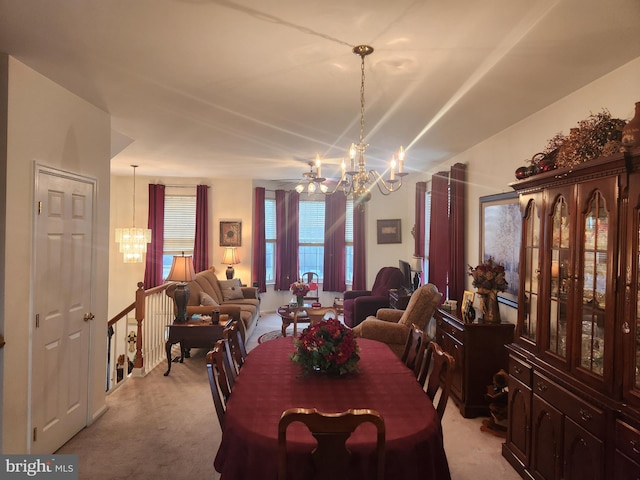 dining space with ceiling fan with notable chandelier and light colored carpet