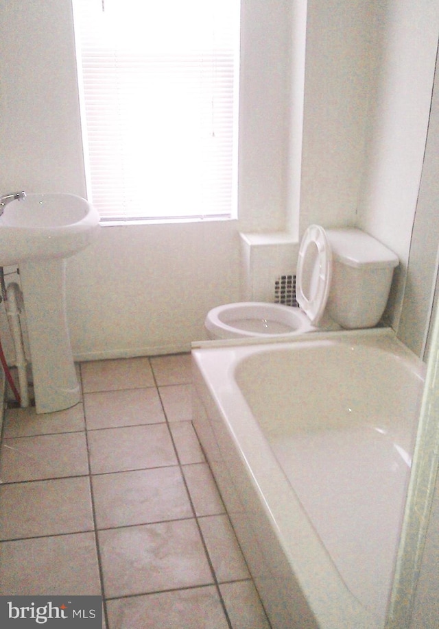 bathroom featuring tile patterned floors, a tub, sink, and toilet