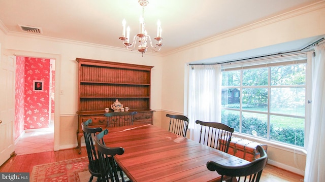 dining space with ornamental molding, light hardwood / wood-style floors, and an inviting chandelier