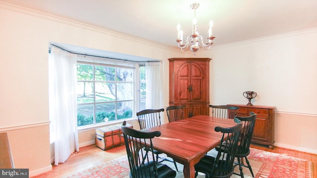 dining space featuring ornamental molding, light hardwood / wood-style floors, and an inviting chandelier