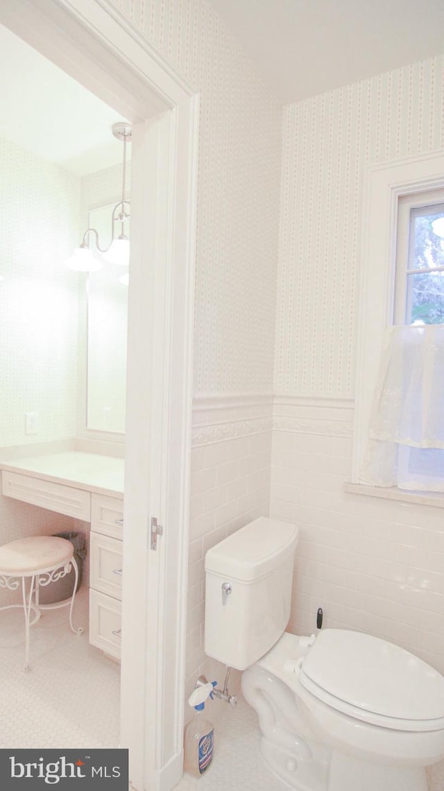 bathroom with tile patterned floors, vanity, toilet, and tile walls