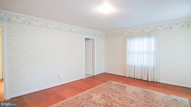 unfurnished room with hardwood / wood-style floors and crown molding