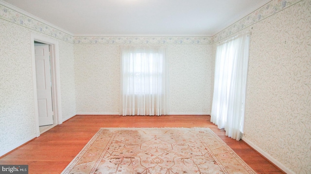 spare room with hardwood / wood-style flooring, a healthy amount of sunlight, and crown molding