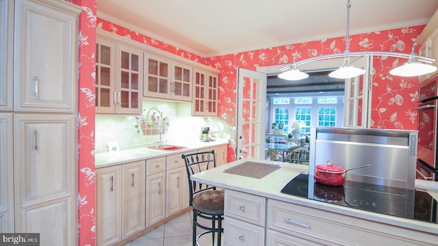 kitchen featuring hanging light fixtures, black electric cooktop, a breakfast bar, light tile patterned floors, and ornamental molding