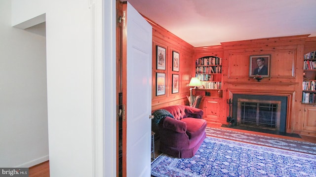 living room with hardwood / wood-style flooring, built in shelves, and wood walls