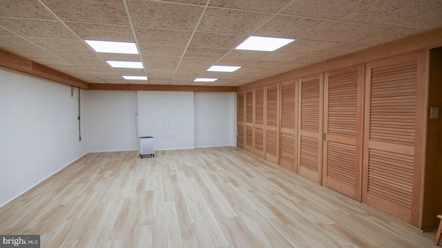 empty room featuring a drop ceiling and light hardwood / wood-style floors