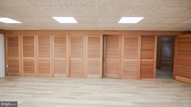 interior space with a paneled ceiling and light hardwood / wood-style floors