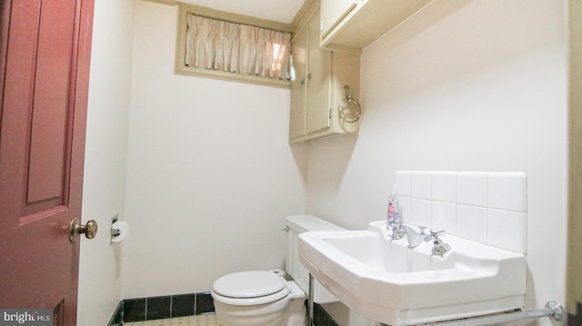 bathroom featuring backsplash, toilet, and sink