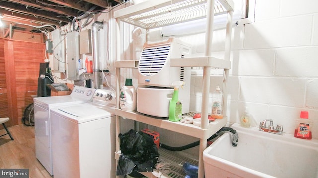 laundry room with light hardwood / wood-style floors, independent washer and dryer, and sink