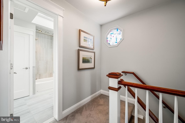 corridor featuring an upstairs landing, light colored carpet, and baseboards