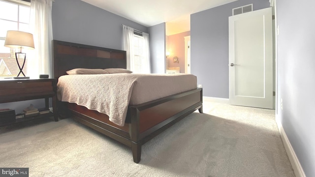 bedroom with visible vents, light carpet, baseboards, and ensuite bathroom