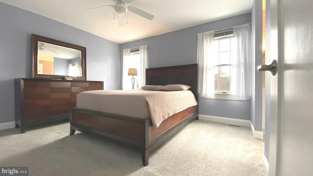 bedroom with visible vents, light colored carpet, baseboards, and ceiling fan