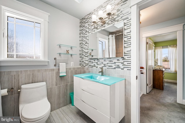 bathroom featuring vanity, tile walls, toilet, and wainscoting