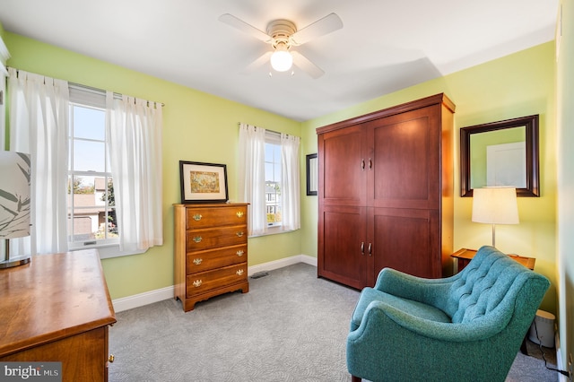 living area featuring visible vents, light colored carpet, baseboards, and ceiling fan