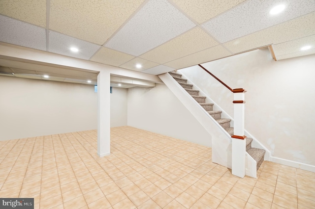 finished basement with stairs, recessed lighting, and a drop ceiling