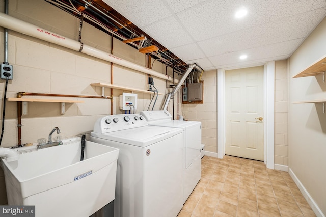 clothes washing area with a sink, baseboards, laundry area, concrete block wall, and separate washer and dryer