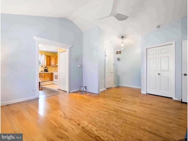 spare room featuring lofted ceiling, a ceiling fan, baseboards, and light wood finished floors