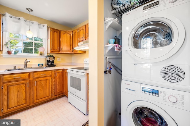 interior space with white range with electric cooktop, under cabinet range hood, brown cabinets, stacked washer / drying machine, and a sink