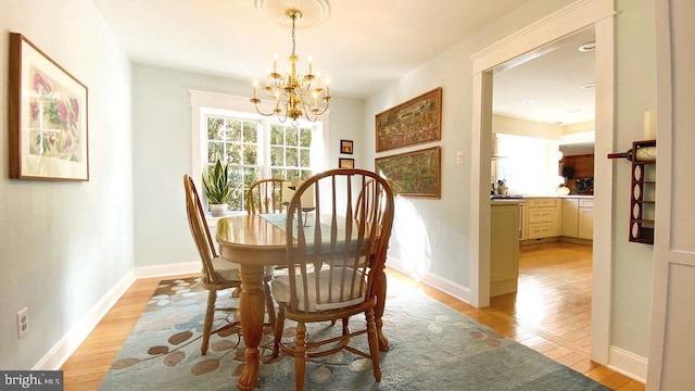 dining area featuring a notable chandelier, baseboards, and light wood-style floors