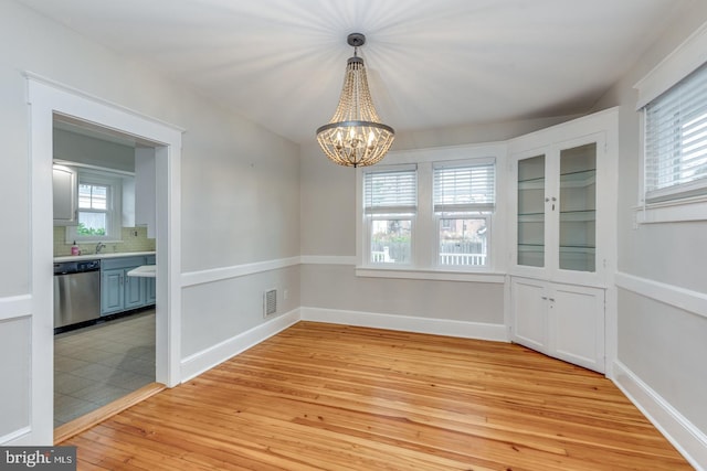 unfurnished dining area with a wealth of natural light, light hardwood / wood-style floors, and an inviting chandelier