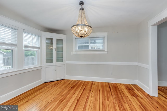 unfurnished dining area featuring a notable chandelier and light wood-type flooring