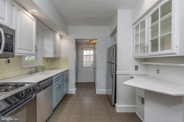 kitchen featuring white cabinets, sink, tasteful backsplash, light tile patterned flooring, and stainless steel appliances