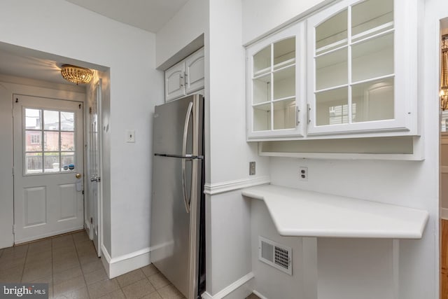 kitchen featuring light tile patterned floors, white cabinetry, and stainless steel refrigerator