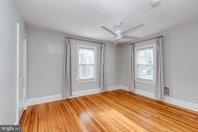 empty room with hardwood / wood-style flooring, ceiling fan, and a wealth of natural light